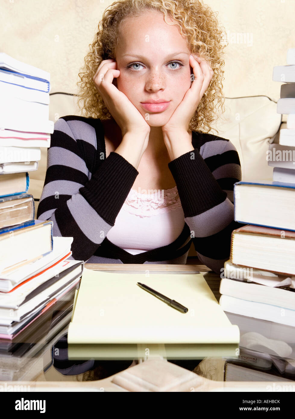 Junge Frau am Schreibtisch mit großen Stapel von Büchern und Notizblock studieren Stockfoto
