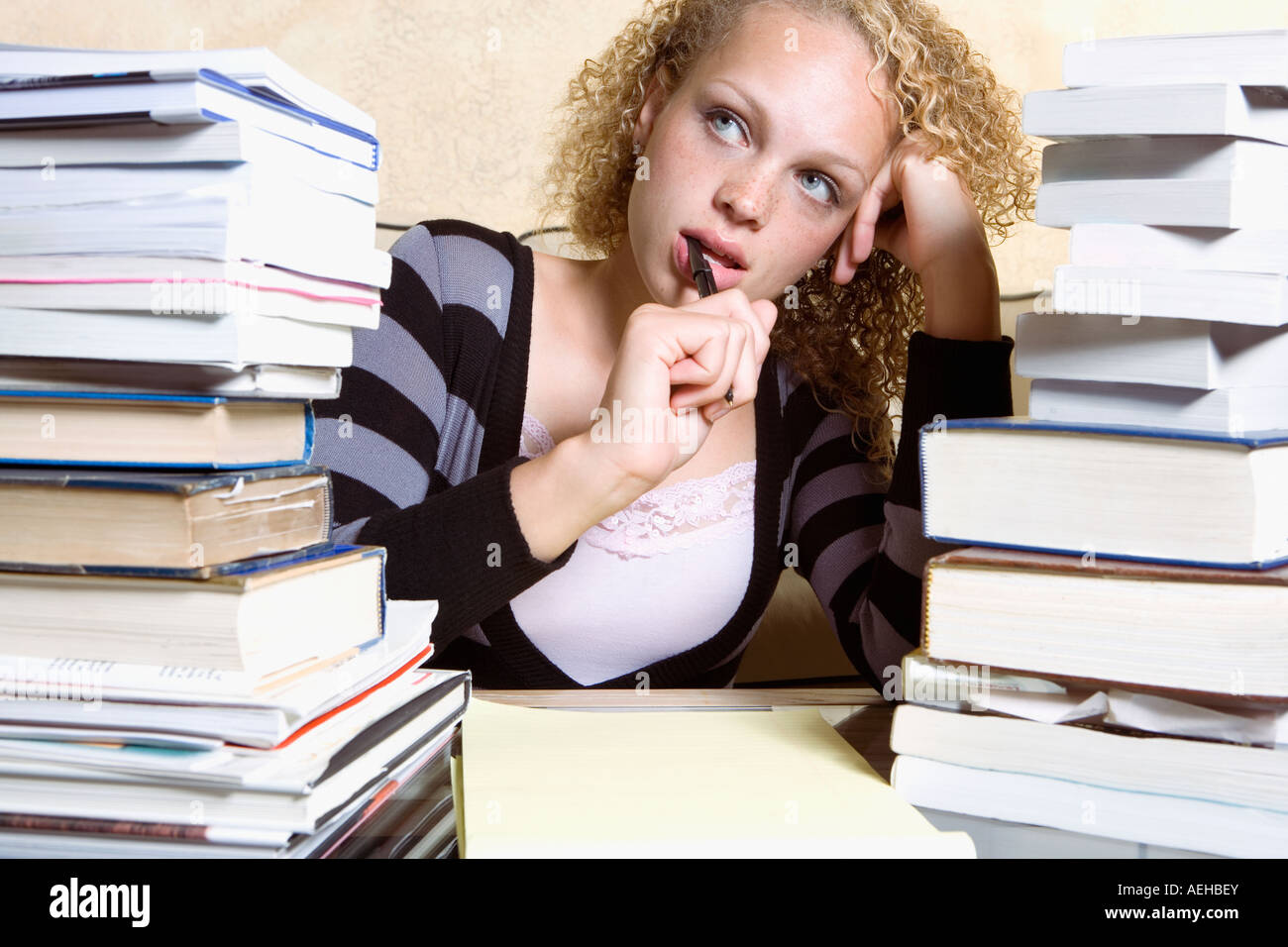 Junge Frau am Schreibtisch mit großen Stapel von Büchern und Notizblock studieren Stockfoto