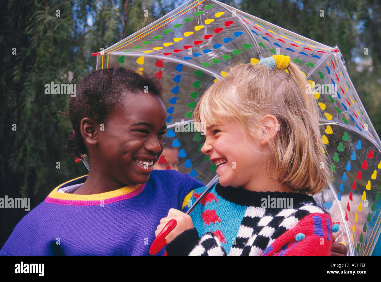 Mädchen 5-7 Jahre alten Holding für Freund lächelnd an regnerischen Tag ethnisch unterschiedlichen ethnischen Vielfalt multikultureller multi kulturellen Herr Myrleen Pearson Stockfoto