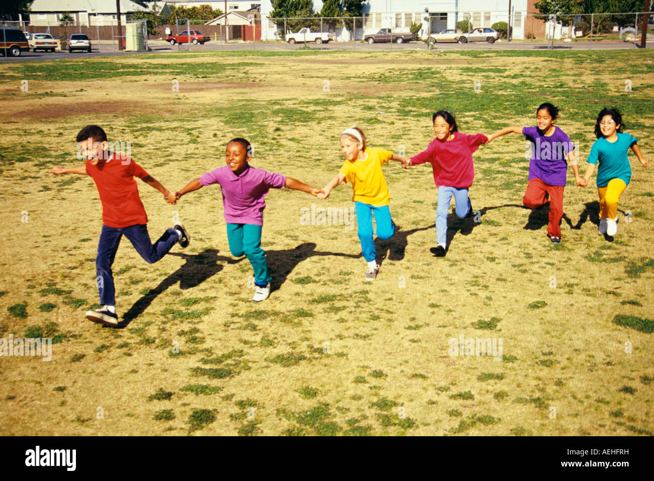 Junge Mensch Menschen Gruppe von ethnisch verschieden Kinder 7 8 9 Jahre Jahre alt halten sich an den Händen läuft lächelnd Spaß POV HERR © Myrleen Pearson Stockfoto