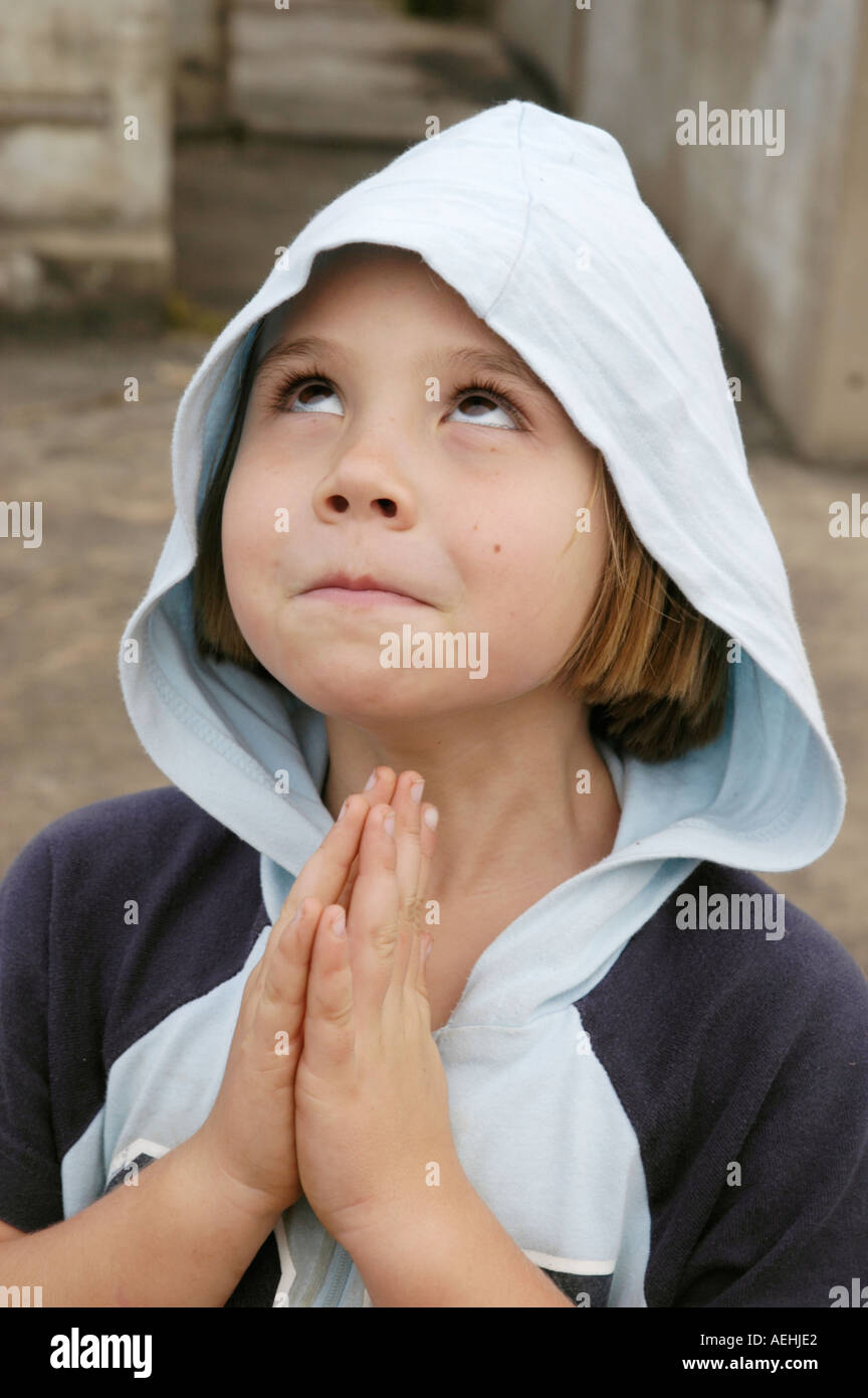 Junge weiße Mädchen vorgibt, Engel mit der Haube ihrer Jacke bis über ihren Kopf und ihre Hände zusammen im Gebet Stockfoto