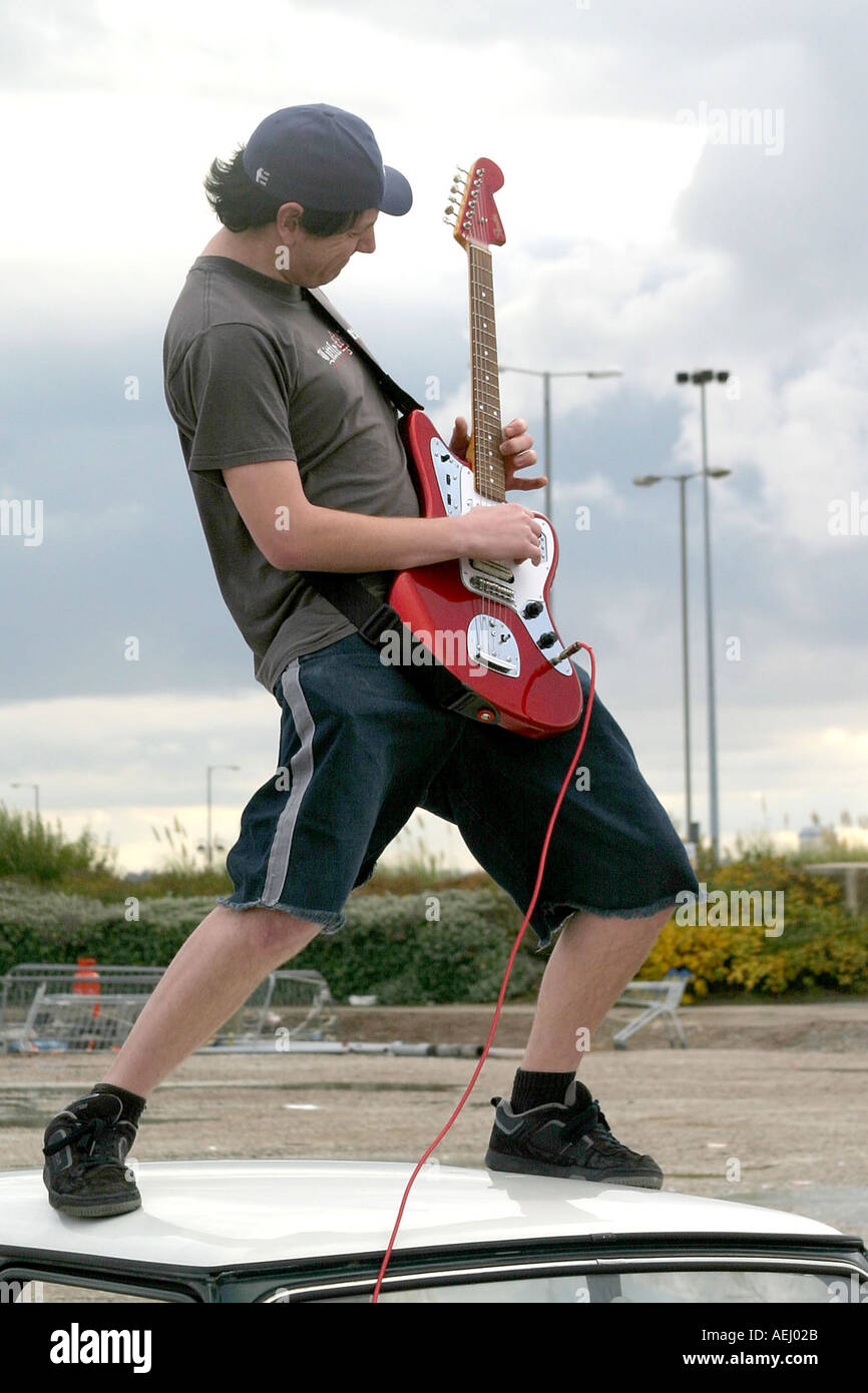 Ein Mann steht auf einem Rover Mini Cooper mit einem Fender Jaguar e-Gitarre Stockfoto