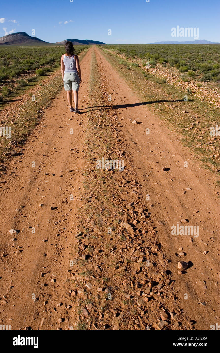 Eine junge Frau zu Fuß entfernt, auf einem Schotterweg Fotografieren in der Nähe von Yavi Provincia de Jujuy, Argentinien Stockfoto