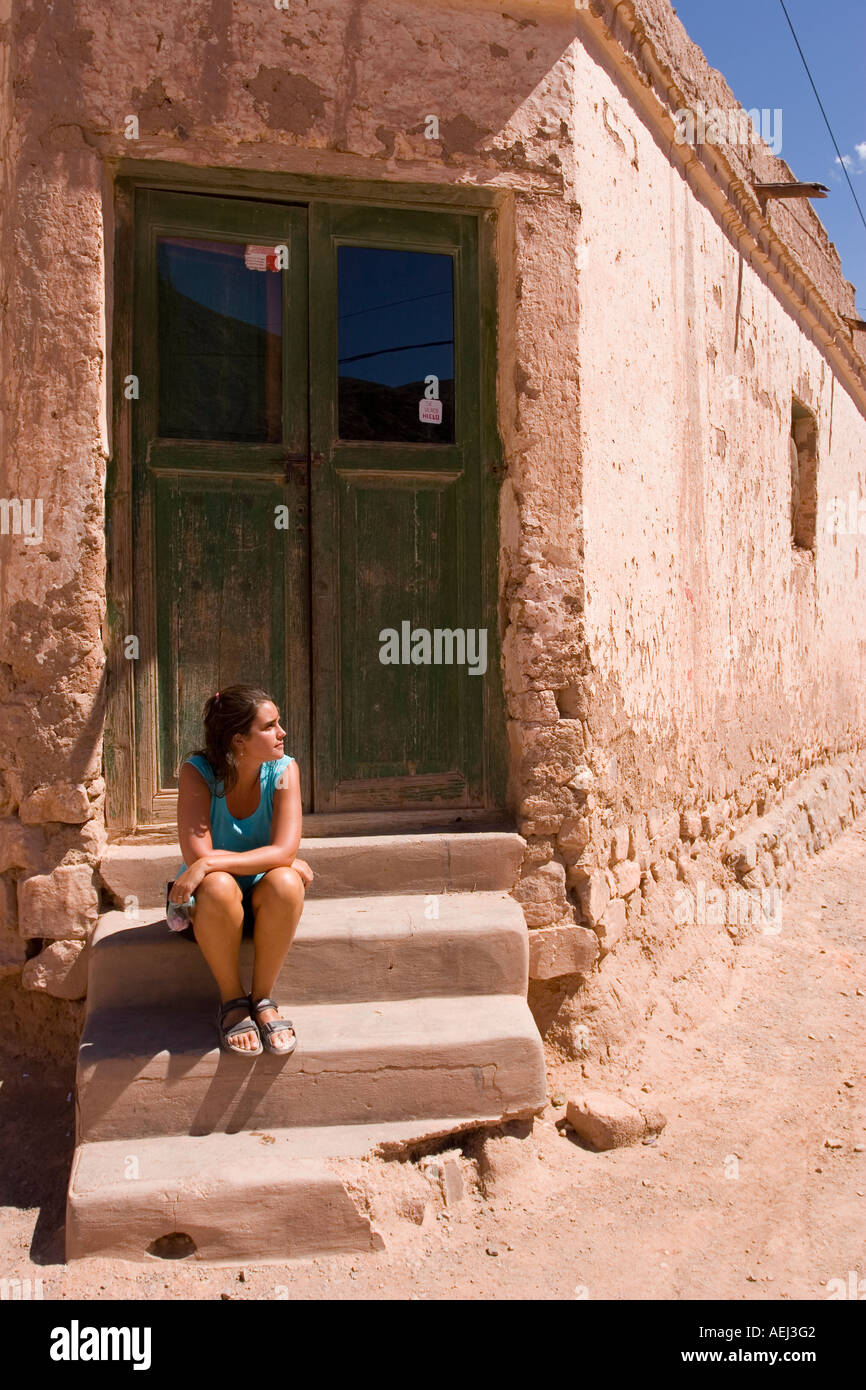 Junge Frau sitzt in der Tür eines Hauses in Purmamarca in der Provincia de Jujuy-Argentinien Stockfoto
