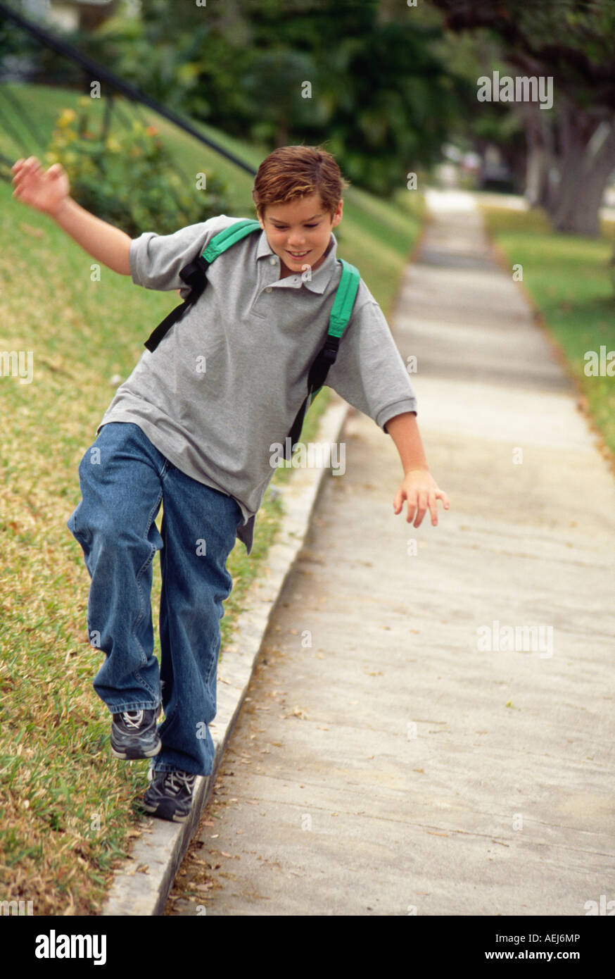 JUNGE, BALANCIEREN AUF BÜRGERSTEIG BORDSTEIN Stockfoto