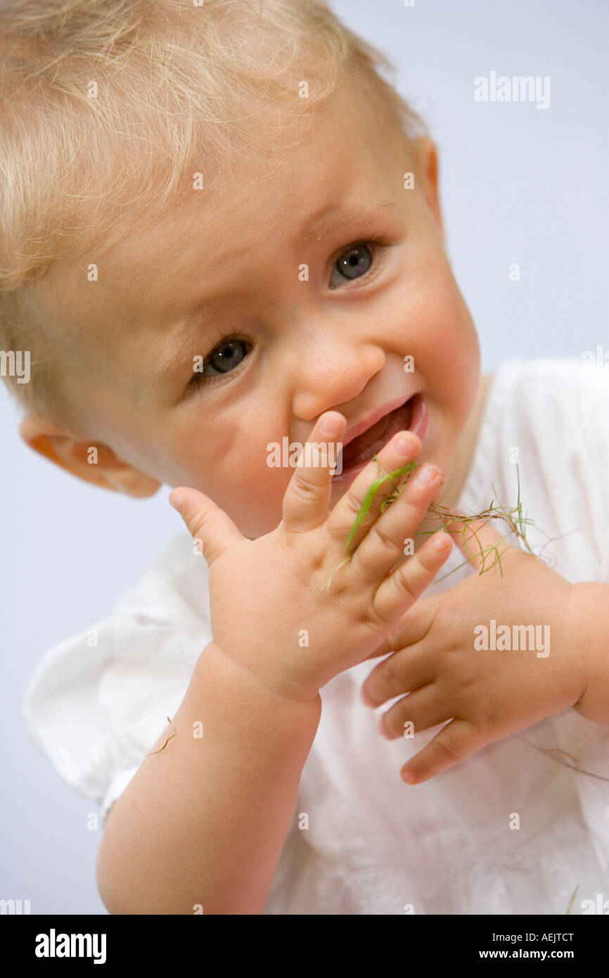 Ein 10 Monate altes Babymädchen spielen mit Grashalmen Stockfoto