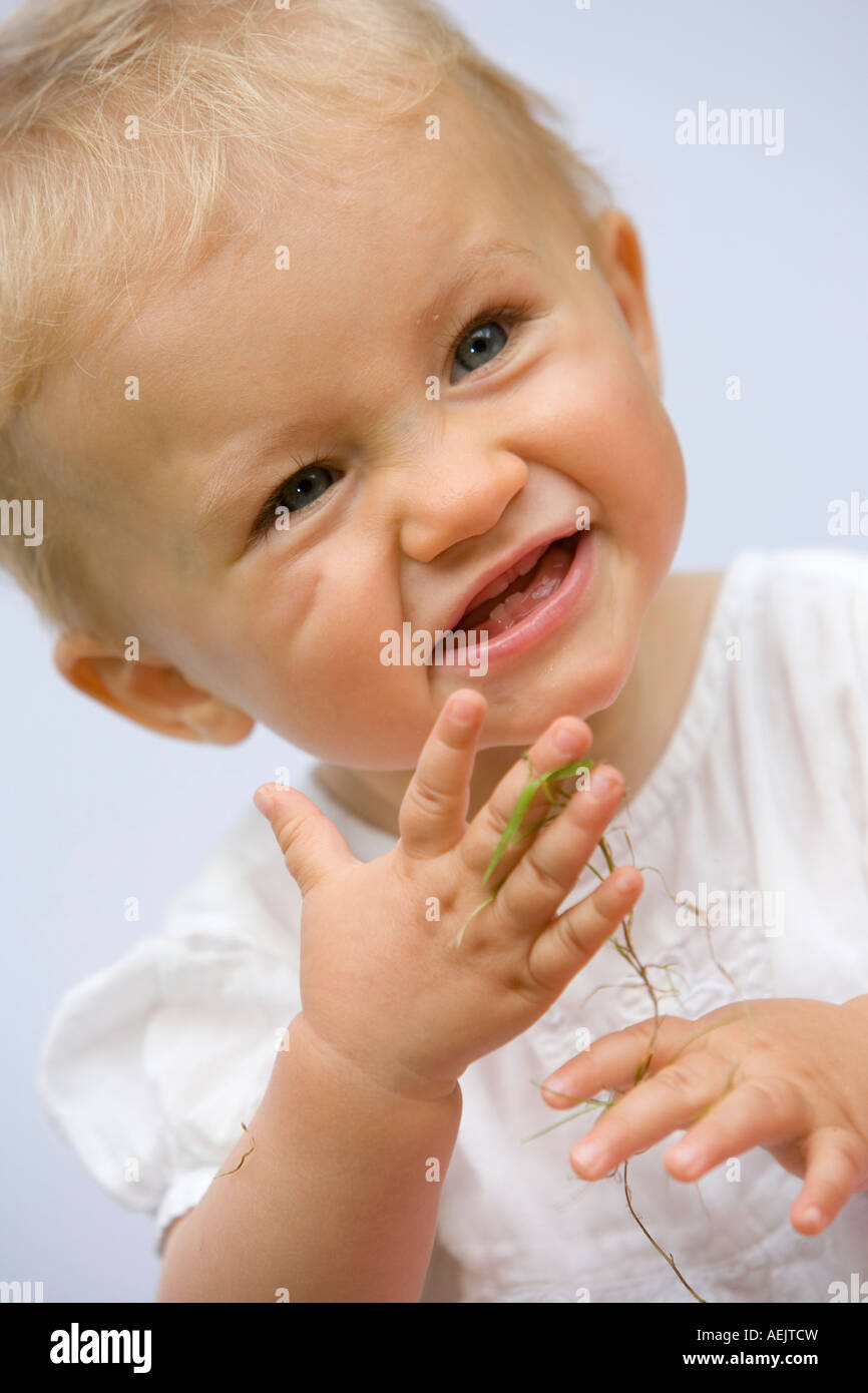 Ein 10 Monate altes Babymädchen spielen mit Grashalmen Stockfoto