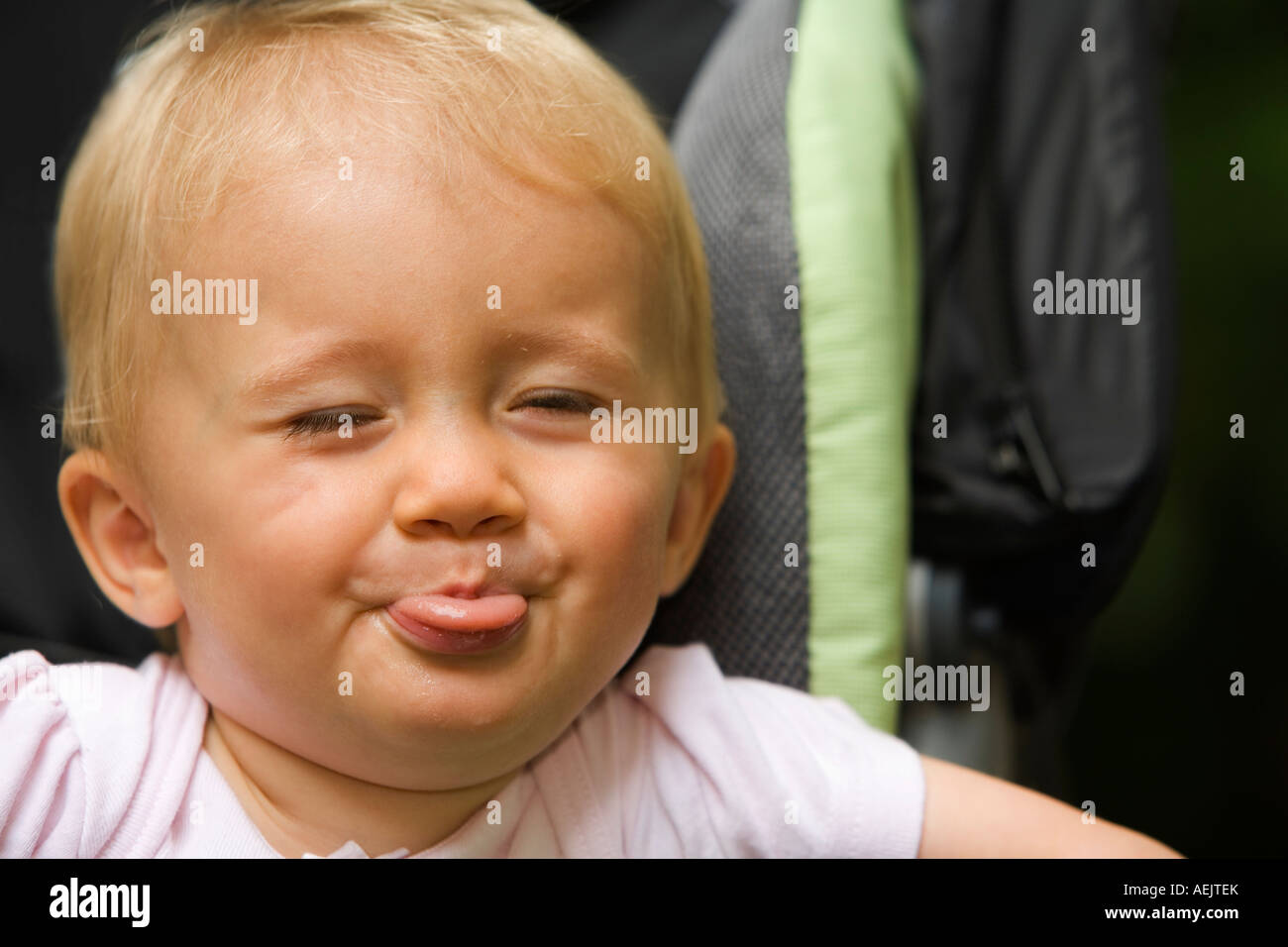 Ein 10 Monate altes Baby Mädchen in einen Kinderwagen, ihre Zunge heraus Stockfoto
