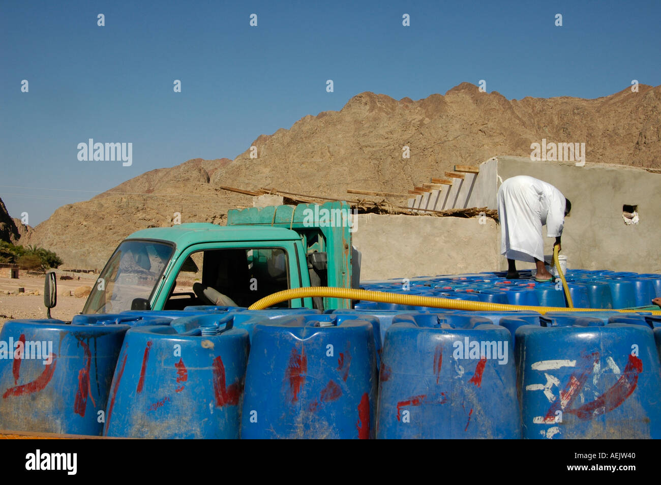 Eine ägyptische Beduinen native Nachfüllen Trinkwasser in Kunststoffbehälter in Wüste Sinai Ägypten Stockfoto
