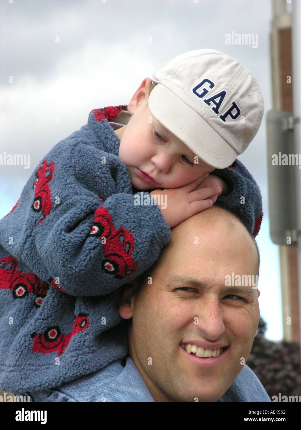 Vater und Sohn ein Kleinkind sitzen auf Schultern in einer menschlichen Interesse bewegender Moment Stockfoto