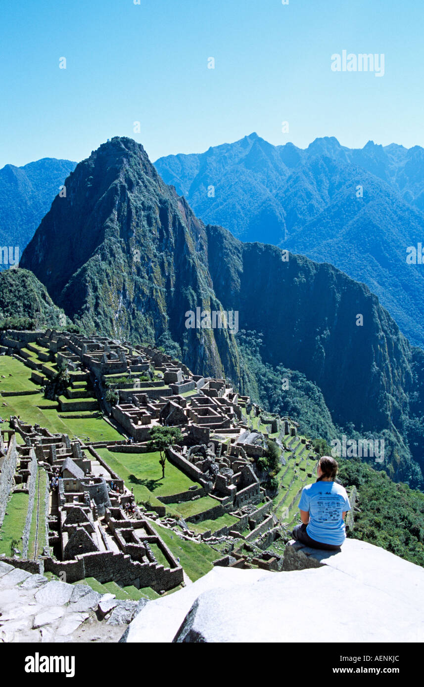 Inkaruinen Machu Picchu, Terrassen, Besucher sitzen auf Felsvorsprung und Huayna Picchu, Peru Stockfoto