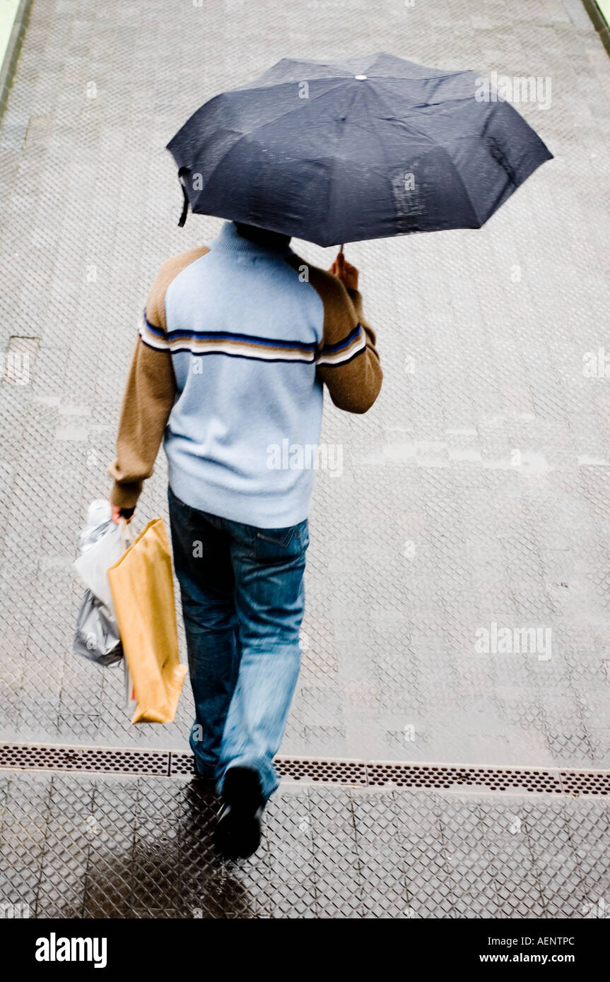 Mann hält Regenschirm und Einkaufstaschen im Regen Birmingham England Stockfoto