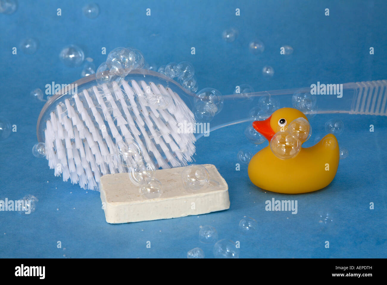 weiße Borsten Bad Pinsel mit klaren Griff hinter länglichen bar Seife und kleine gelbe Gummiente mit Seifenblasen Stockfoto