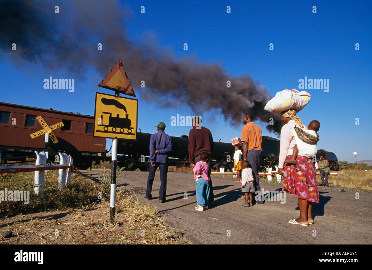 Simbabwe Bulawayo, Menschen stehen am Bahnübergang mit Dampfzug Stockfoto