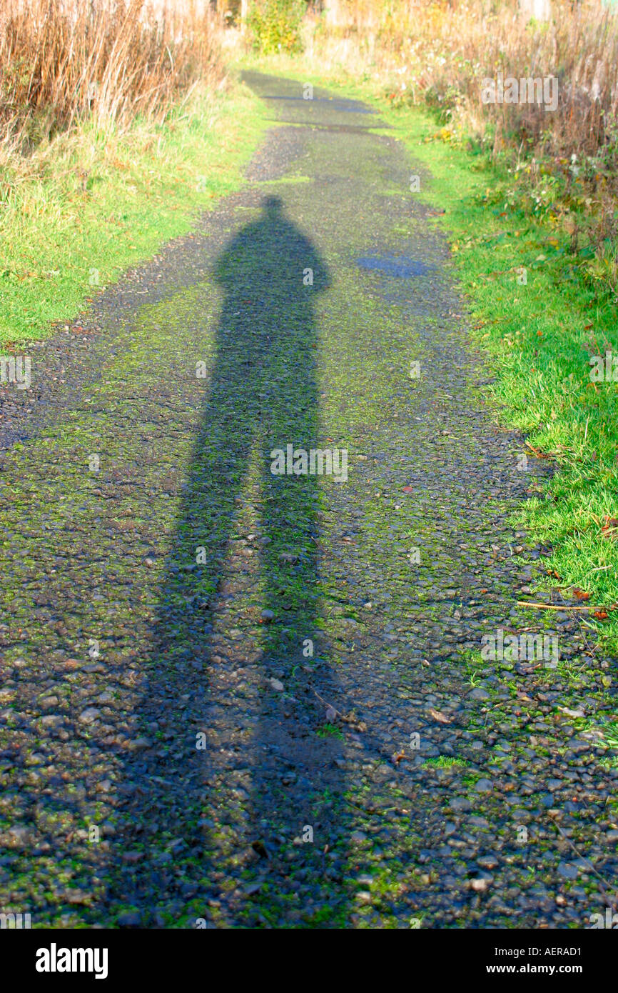 Schatten des Mannes auf Fußweg durch die späte Nachmittagssonne länglich Stockfoto