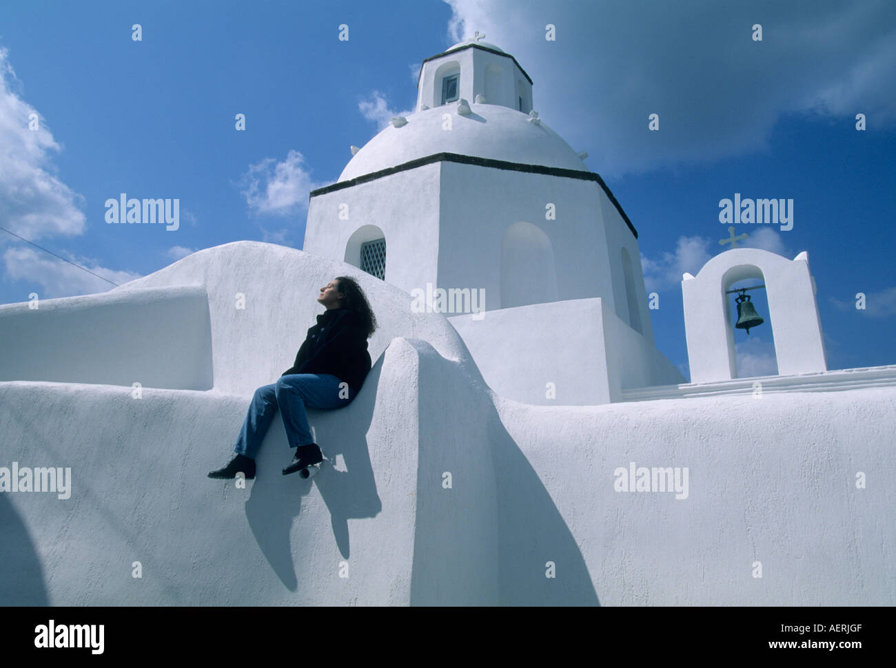 Griechenland, Kykladen, Santorini, griechische orthodoxe Kirche mit Blick auf die Ägäis, Frau sitzt an Wand, Thira Stockfoto