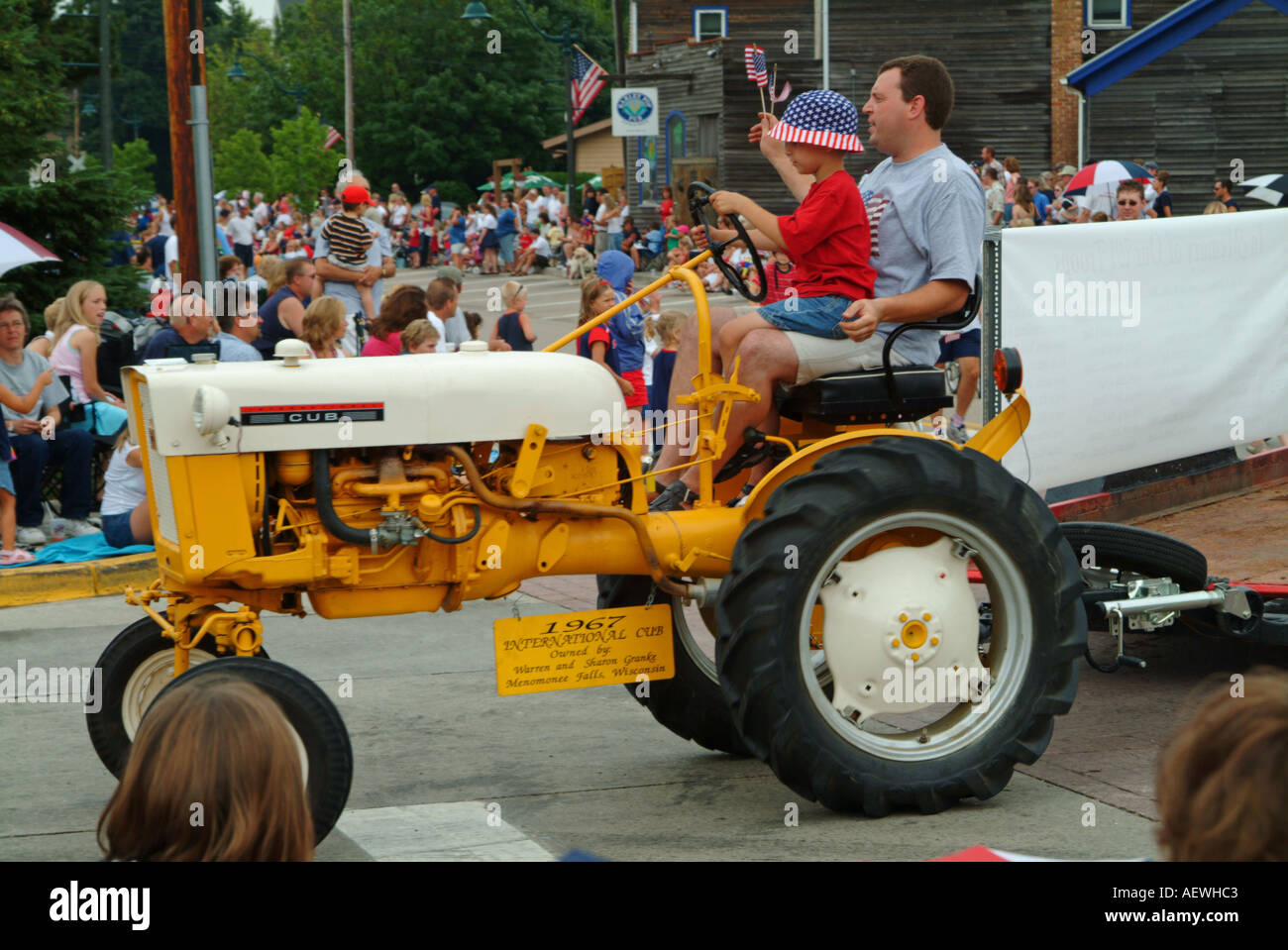 1967 internationale Traktor angetrieben durch ein kleines Kind in Vaters Schoß am 4. Juli Parade Stockfoto