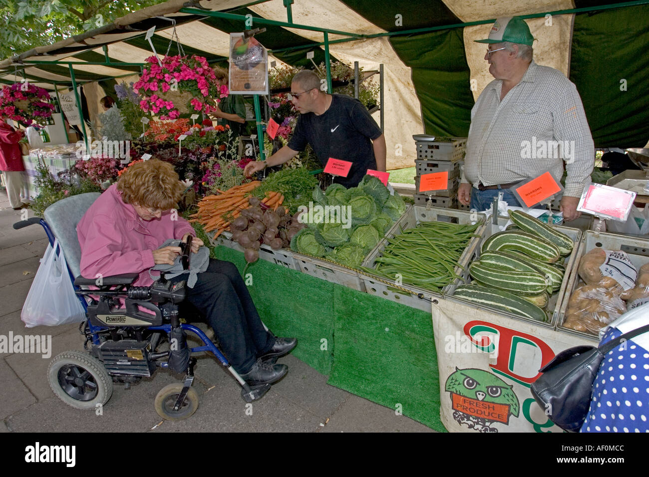 Frau im Rollstuhl kaufen Gemüse am Bauernmarkt auf Promenade Cheltenham UK Stockfoto