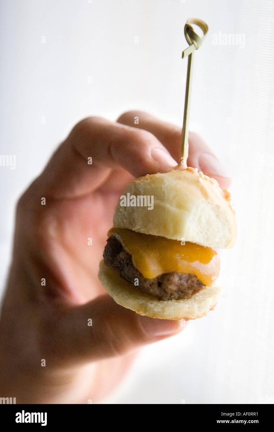 Frau mit Mini-Cheeseburger bei cocktail-party Stockfoto