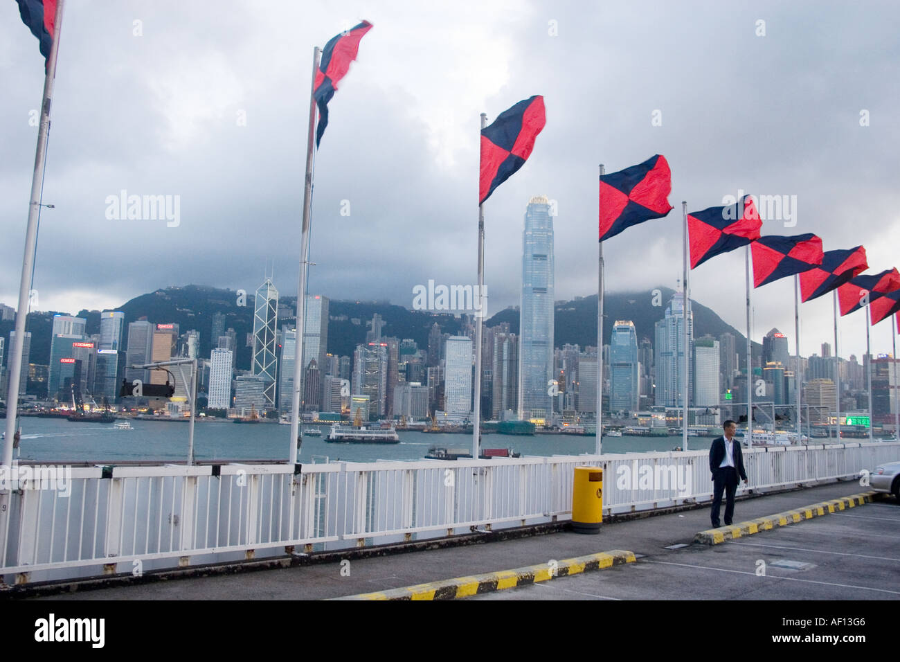 Fahnen flattern im Wind auf einem Parkplatz auf dem Dach in Tsim Sha Tsui.  Hong Kong Skyline von dramatischen Nacht hinter. Stockfoto