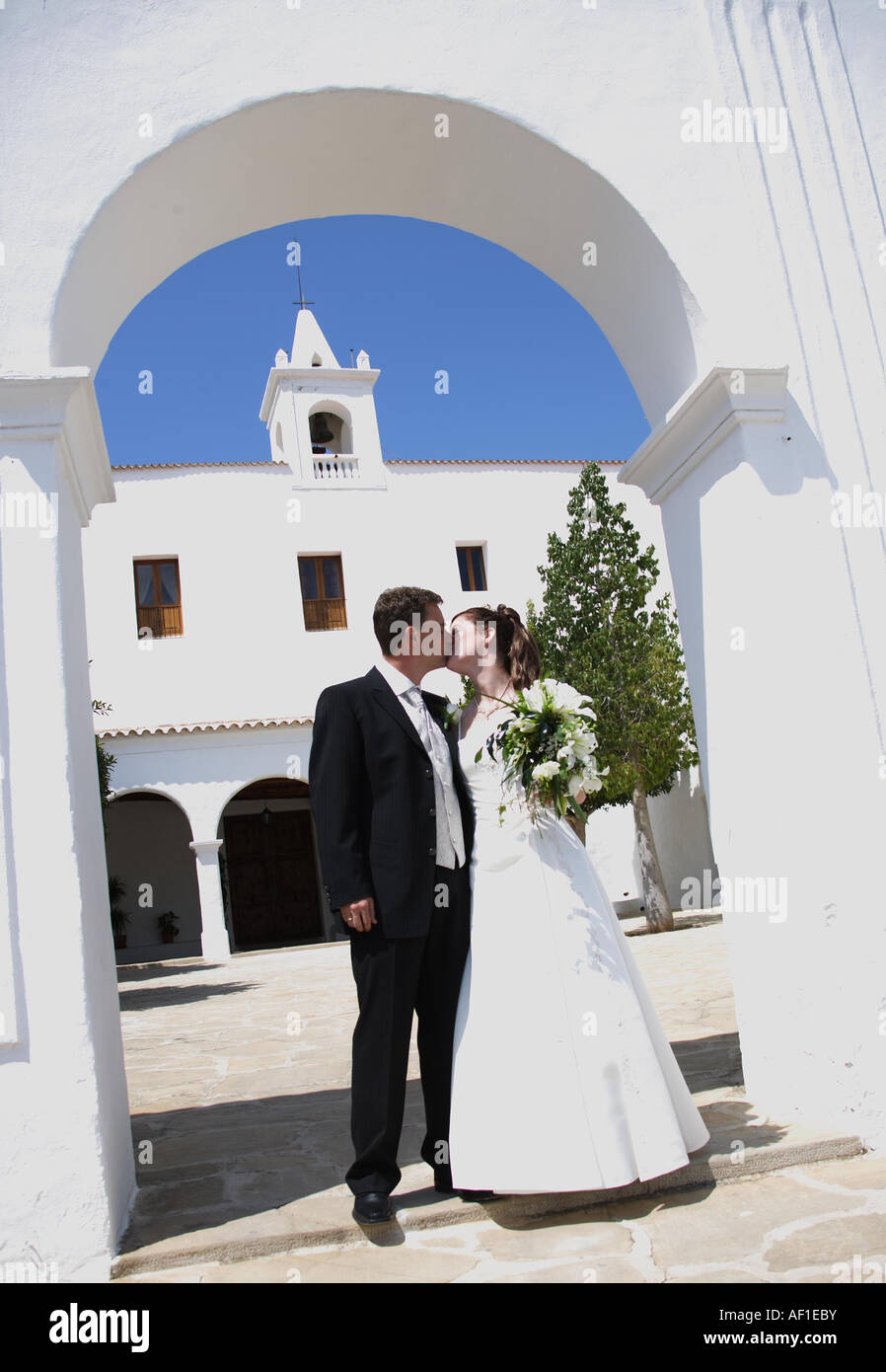 Frisch Getrautes Brautpaar Kuesst Sich Vor der Kirche Esglesia de Sant Miquel / junge Brautpaar gerade geheiratet vor Kirche Stockfoto