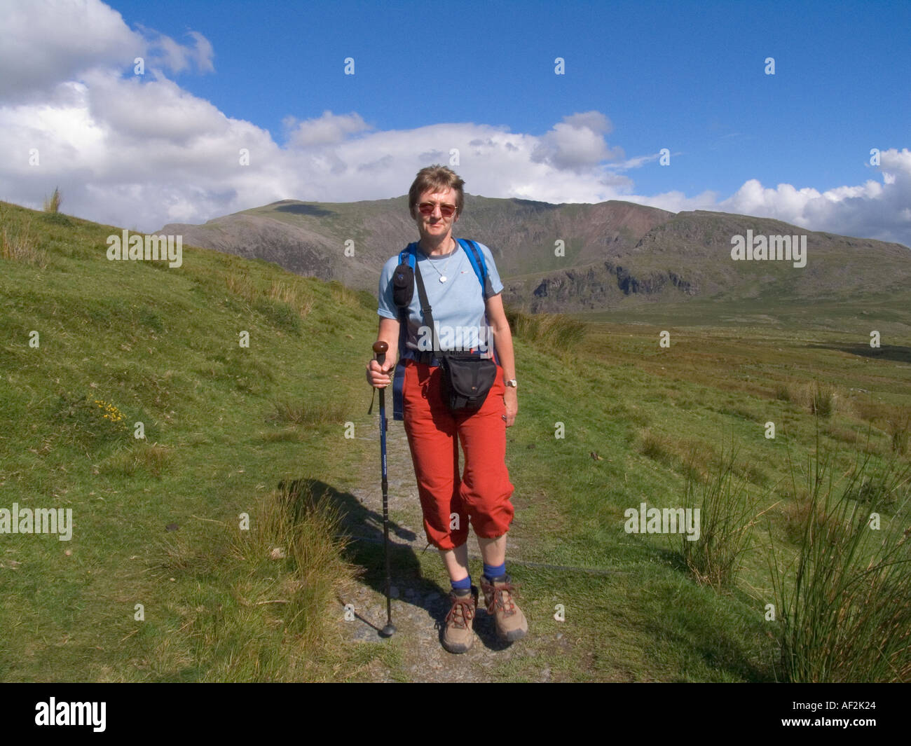 SNOWDON Ranger Pfad GWYNEDD UK August passende Frau zu Fuß entlang, weg von Snowdon Snowdon Ranger im Hintergrund auf einem schönen August Sommer Tag Stockfoto