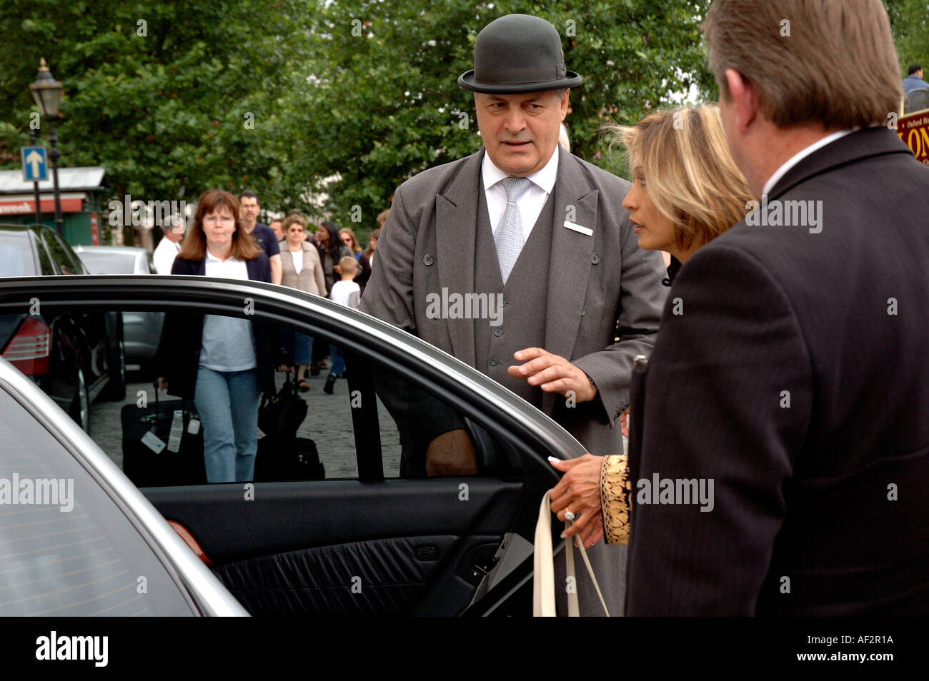 Türsteher mit Melone am zentralen London Hotel helfende Besucher in Limo. Stockfoto