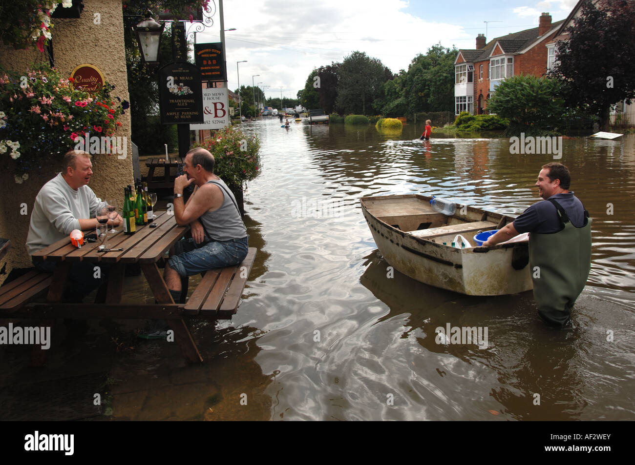 Vermieter des überfluteten Queens Head Pub in Longford Gloucester in England Juli 2007 Wein trinkt und spricht mit einem vorbeifahrenden Boot Stockfoto
