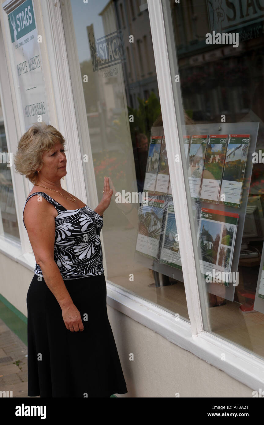 Eine Frau, die in das Fenster eines Makler-Büros in Barnstaple, North Devon. Stockfoto
