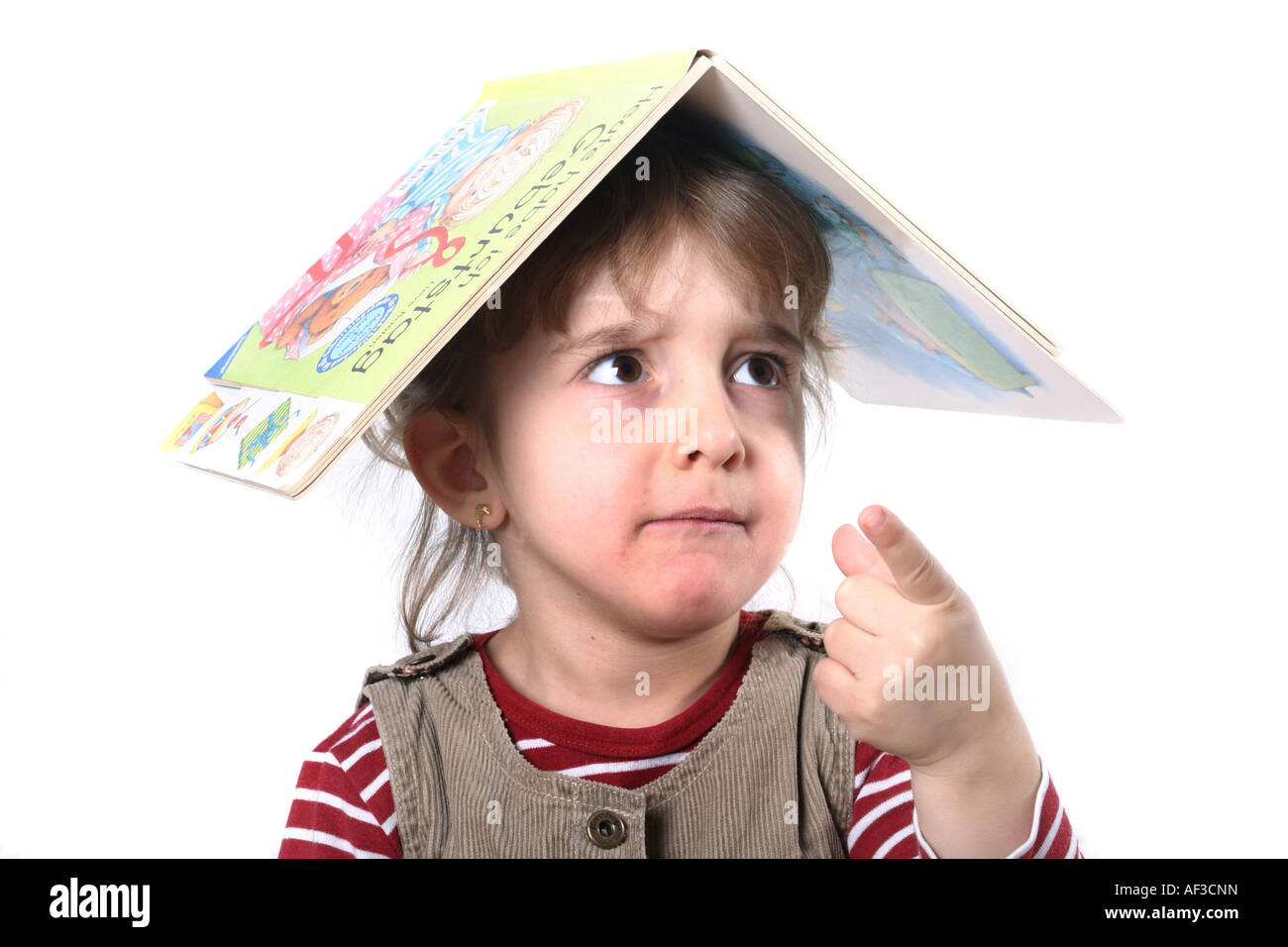 Kind mit einem Buch auf den Kopf Stockfoto