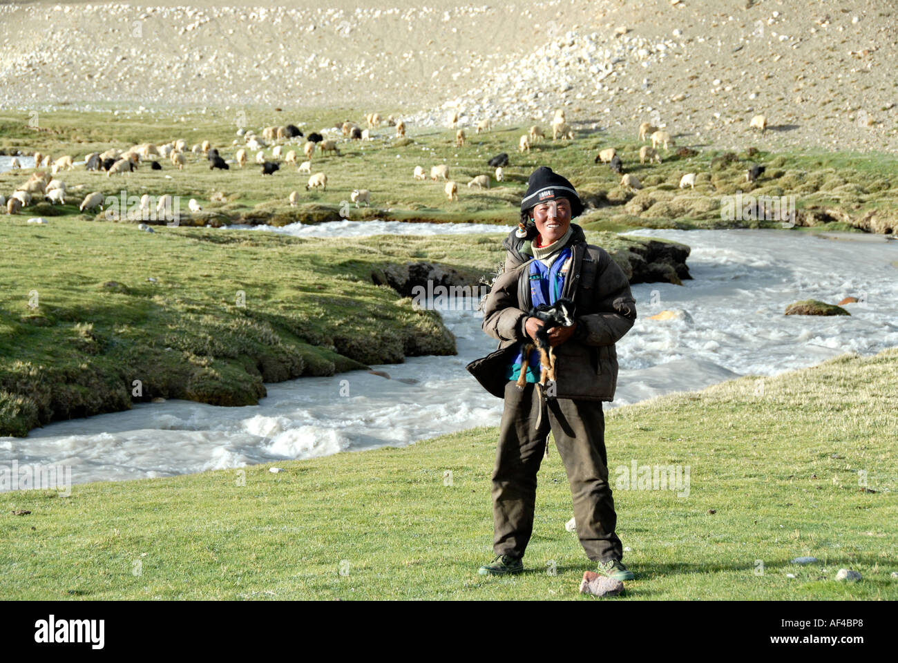 Hirte trägt ein Lamm in seinen Armen an einem Fluss in der Nähe von Lungchang Tibet China Stockfoto