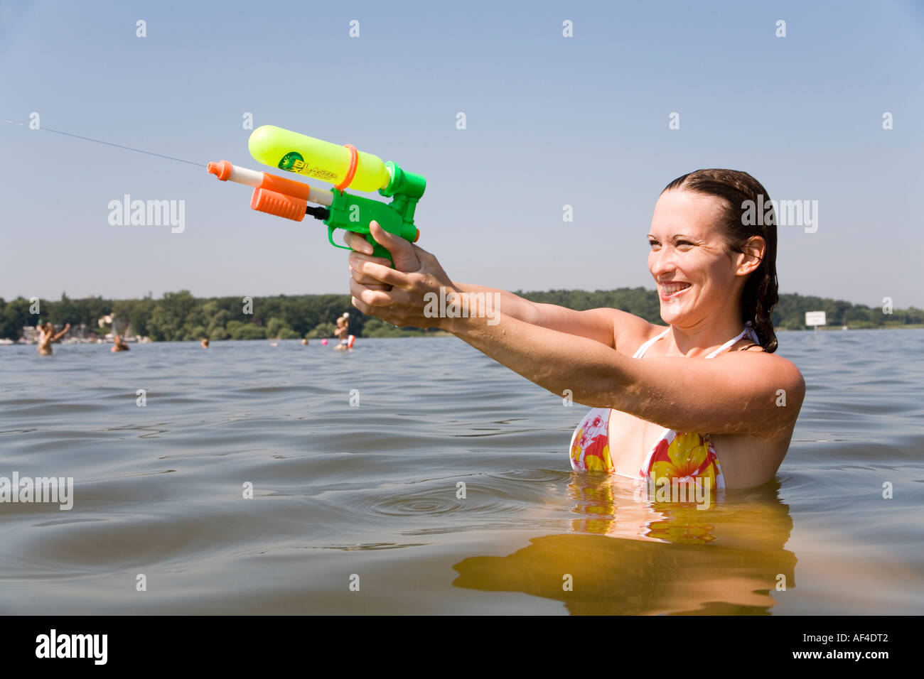 Junge Frau (30) mit einer Pumpe Pistole im See, Badestrand Wannsee, Berlin Stockfoto