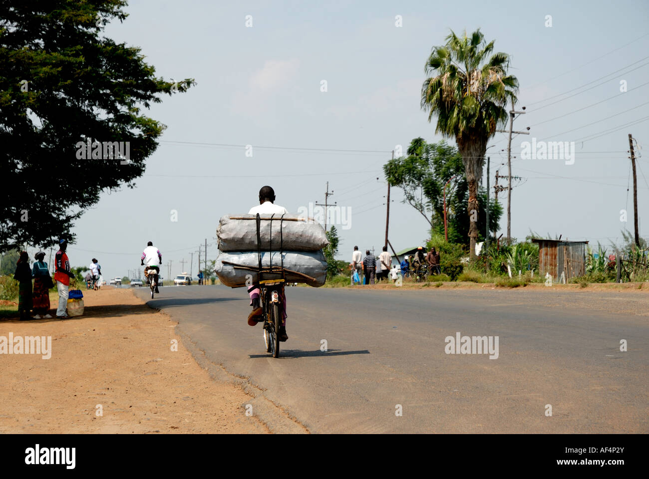 Schwarze Afrikaner, die schwer beladenen Fahrrad fahren entlang der Straße Maseno Kisumu in Western Kenia in Ostafrika Stockfoto