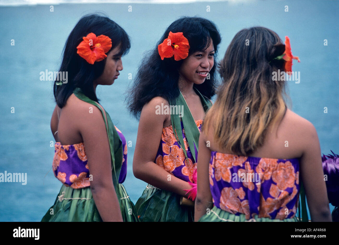 Seite Rückansicht Porträt von drei schöne lokale dunkel gehäutet Mädchen hawaiianische Tänzerinnen in blau und rot blühenden Blusen Hawaii Stockfoto