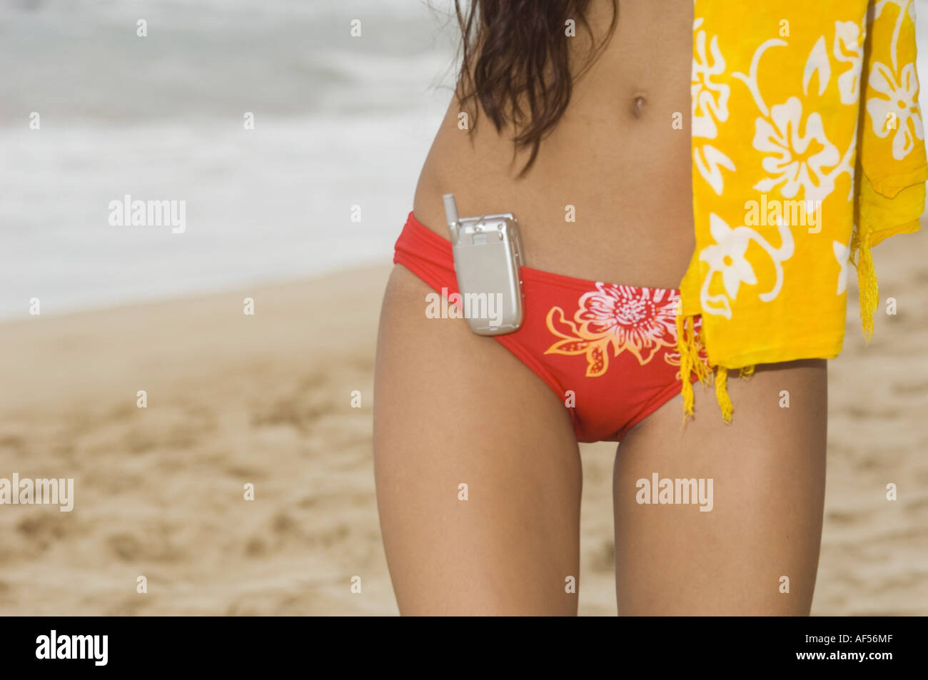 Nahaufnahme eines Mobiltelefons an das Bikini-Unterteil einer Frau hängen Stockfoto