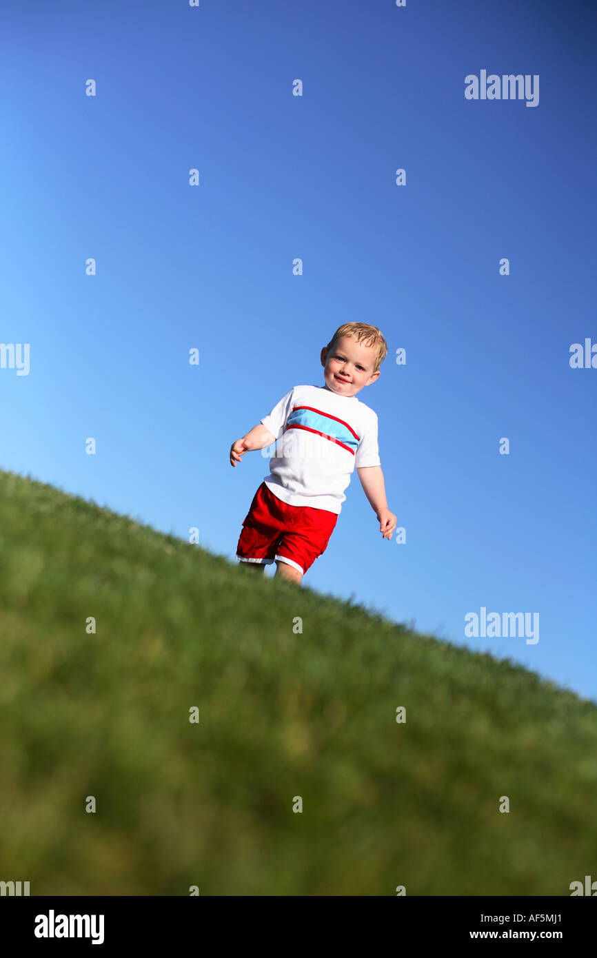 Zwei Jahre alten Jungen zu Fuß auf dem Rasen mit strahlend blauem Himmel. Stockfoto