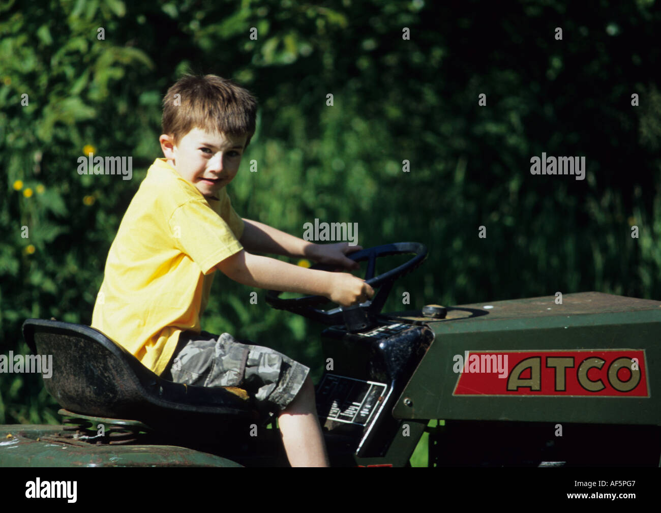 Sechs Jahre alter Junge fahren Rasenmäher im Vereinigten Königreich Stockfoto