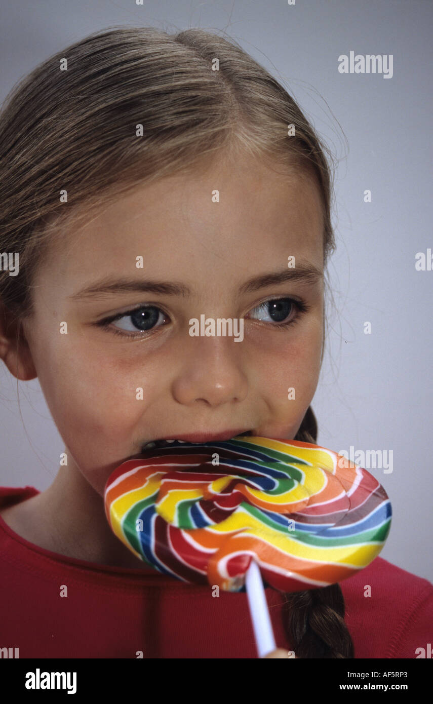 Mädchen in bunten Lolly zu beißen Stockfoto