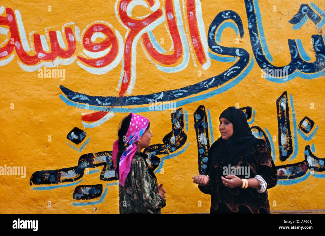 Ägypten Luxor, Frauen im Chat vor der bemalten Wand Stockfoto