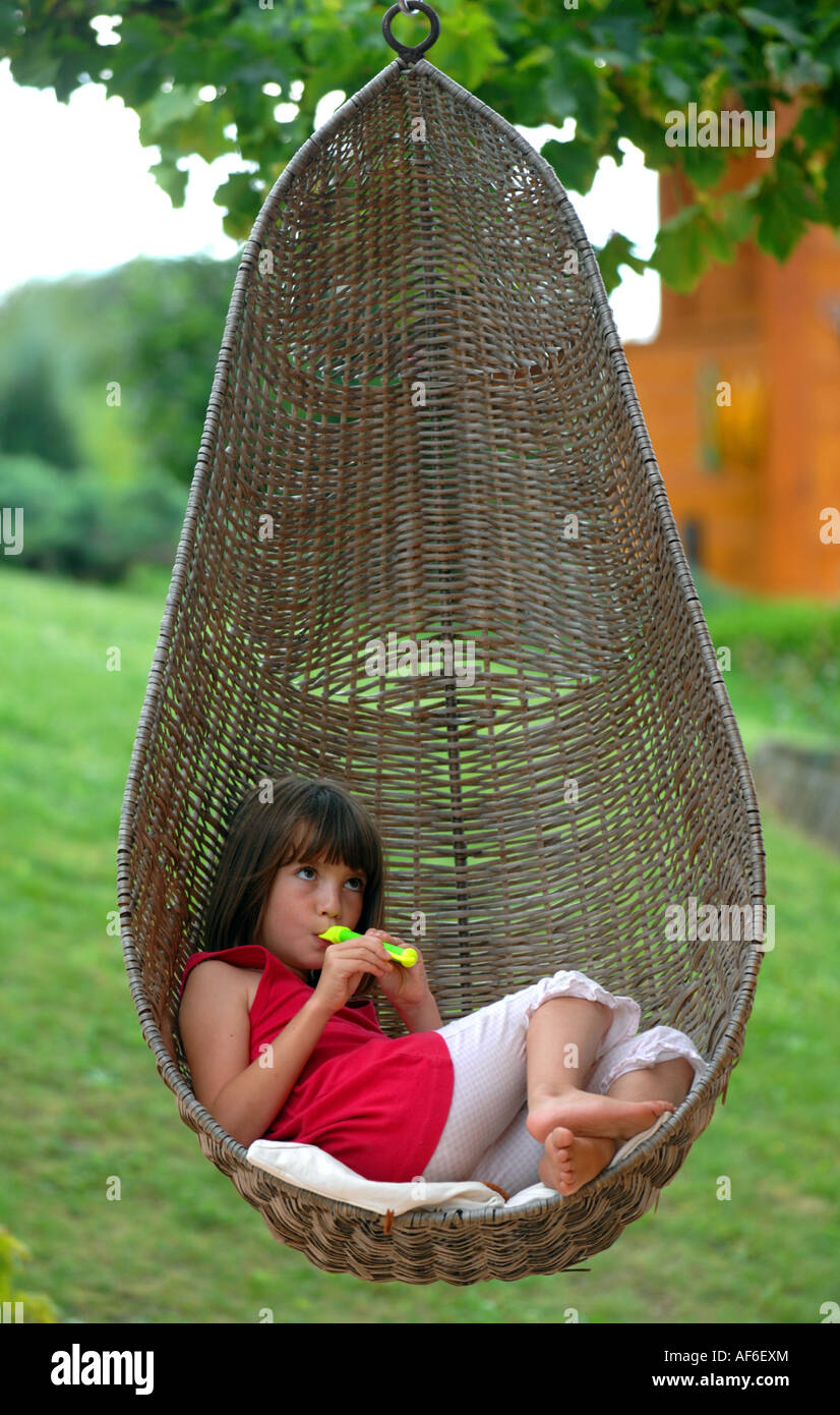 Hängenden Korb Korbstuhl, Mädchen mit hängenden Korb Stuhl und spielt  Querflöte Stockfotografie - Alamy