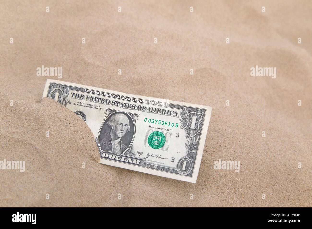 Einem US-Dollar teilweise vergraben im Sand Fokus auf dem Zettel Stockfoto