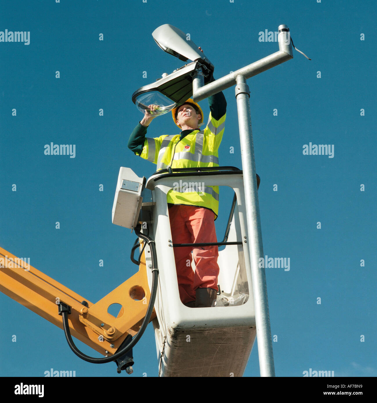 Mann steht auf erhöhten Arbeitsbühne Hubarbeitsbühne, Aufrechterhaltung einer Straßenlaterne. Stockfoto