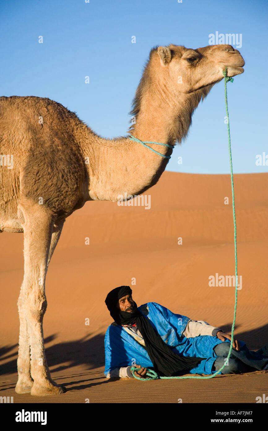 Hashmi Mohammed, ein Tuareg-Mann und sein Kamel Rest in der Sahara Wüste von Marokko Stockfoto