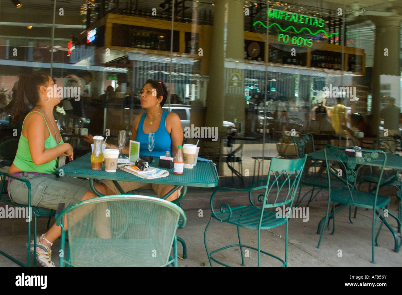 Zwei junge Frauen sitzen an einem Cafe Tisch lachen im French Quarter. New Orleans, Louisiana, USA Stockfoto