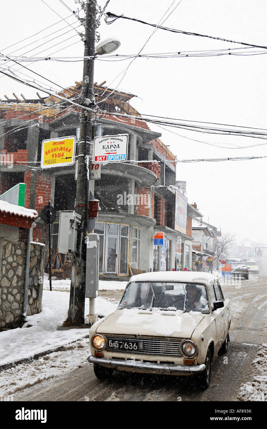 Ein altes Auto fährt durch Straßen Matsch im Skigebiet Bansko, Pirin-Gebirges, Bulgarien Stockfoto