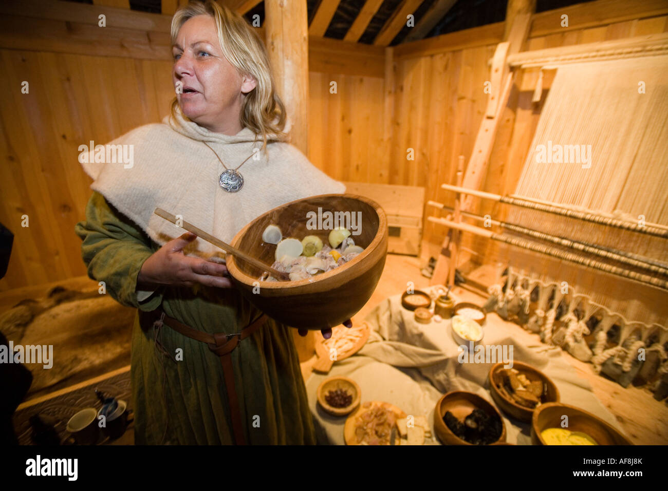 Eine Frau dient ein Wikinger-Essen in einer rekonstruierten Langhaus an Qassiarsuk. der Ort waren die ersten Wikinger mit Erik der rote sett Stockfoto