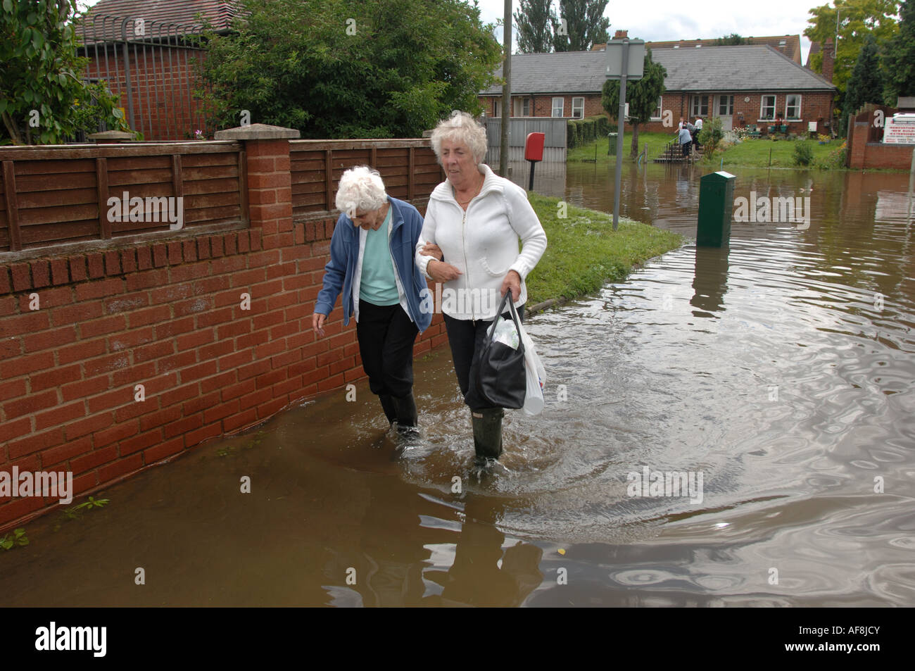 Zwei alte Damen, die zu Fuß durch Überschwemmungen im Bereich Longford von Gloucester in England Juli 2007 nach einem schweren Hochwasser Stockfoto