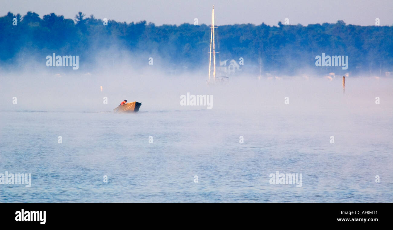 Fischer Befugnisse gegenüber den Kopf Gewässern des White Lake, gefolgt von einem Segelboot, die Rückkehr in die marina Stockfoto