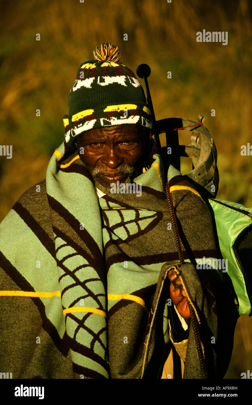 Porträt eines bärtigen Basotho-Mannes in eine Decke gehüllt, trägt eine Wollmütze und hält eine Metall-Knopf-Kerrie über seine Schulter Stockfoto