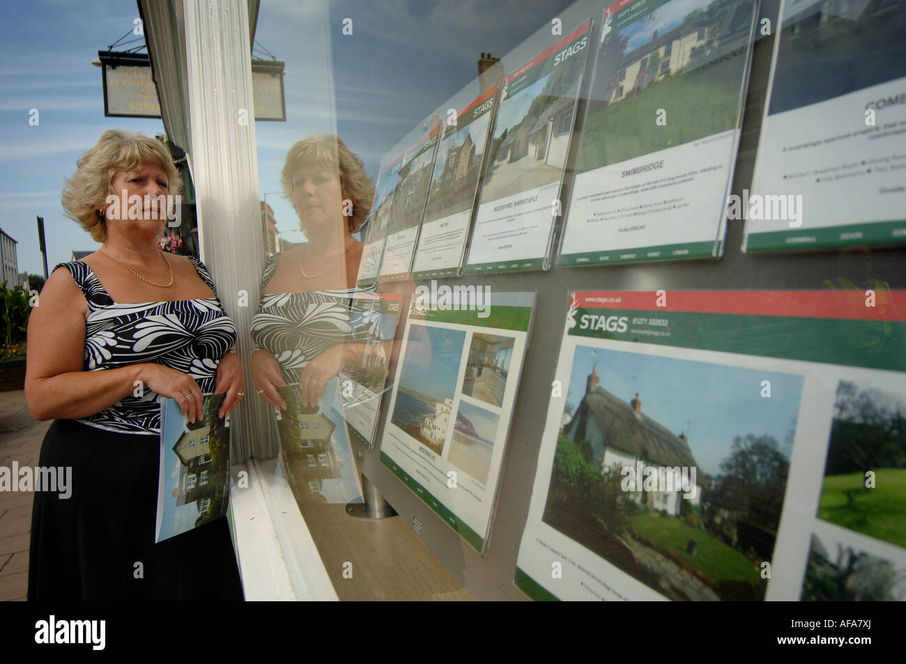 Eine Frau, die in das Fenster eines Makler-Büros in Barnstaple, North Devon. Stockfoto